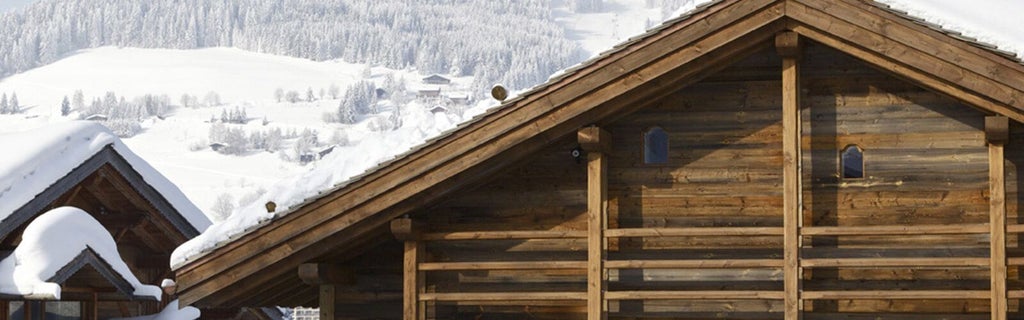 Luxurious alpine chalet bedroom with rustic wooden walls, plush white bedding, and panoramic mountain views in French ski resort