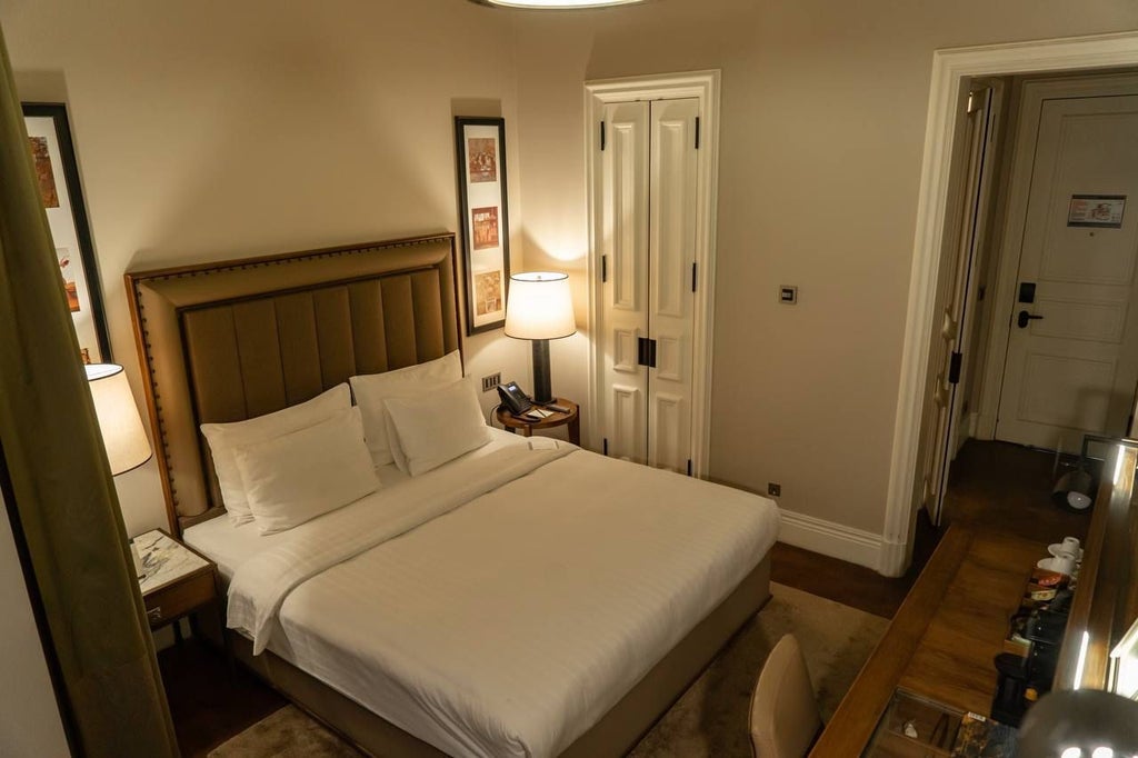 Elegantly designed classic king room featuring plush white bedding, rich dark wood furnishings, and sophisticated urban luxury in historic Istanbul hotel setting