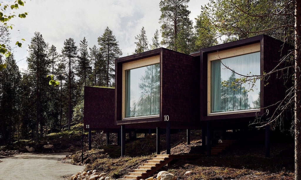 Luxurious Arctic TreeHouse Suite with panoramic windows overlooking snowy landscape, modern Nordic design, warm wooden interior, and cozy minimalist sleeping area.