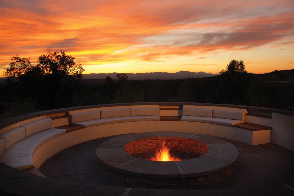 Adobe-style luxury resort with terra cotta walls, wood beams and private terraces nestled amid high desert landscape in Santa Fe