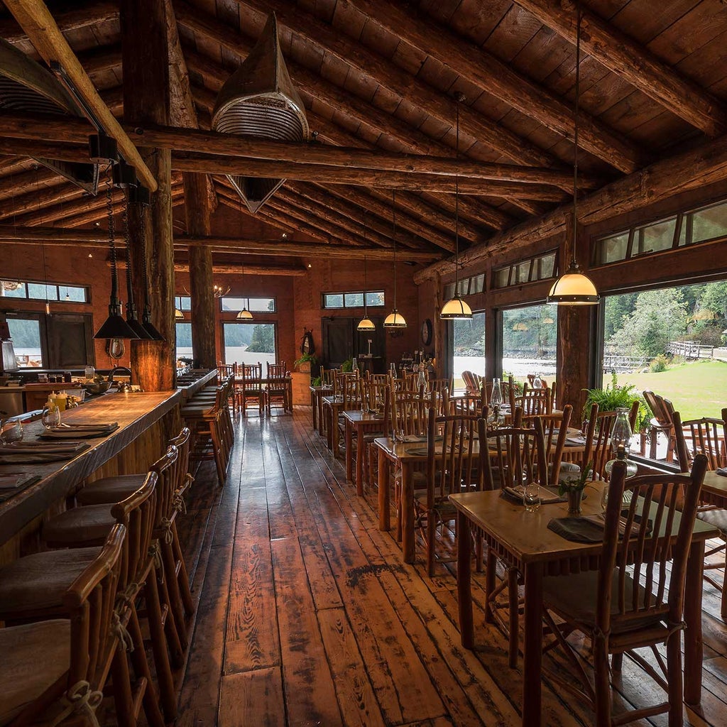 Luxury safari-style tent with king bed overlooking pristine Canadian wilderness, featuring private deck and mountain backdrop