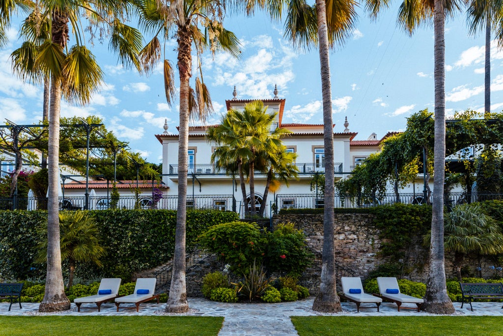 Elegant stone facade of Vintage House Hotel overlooking Douro River, with manicured gardens and luxurious terrace seating in Portugal