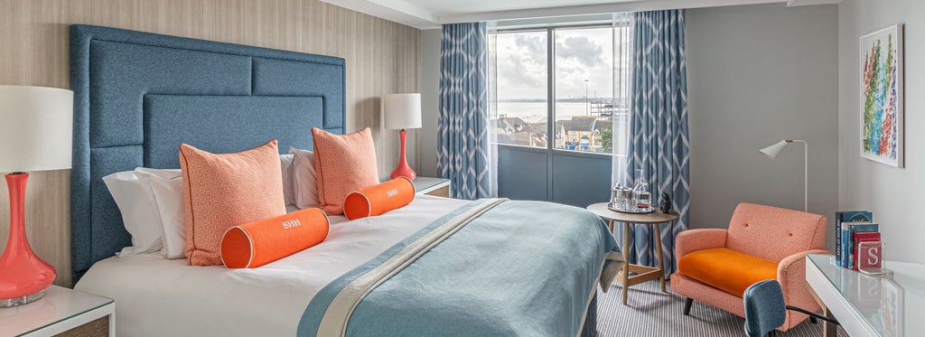 Luxurious deluxe hotel room with expansive marina view, showcasing modern design, crisp white bedding, and elegant maritime-inspired decor in Southampton, UK