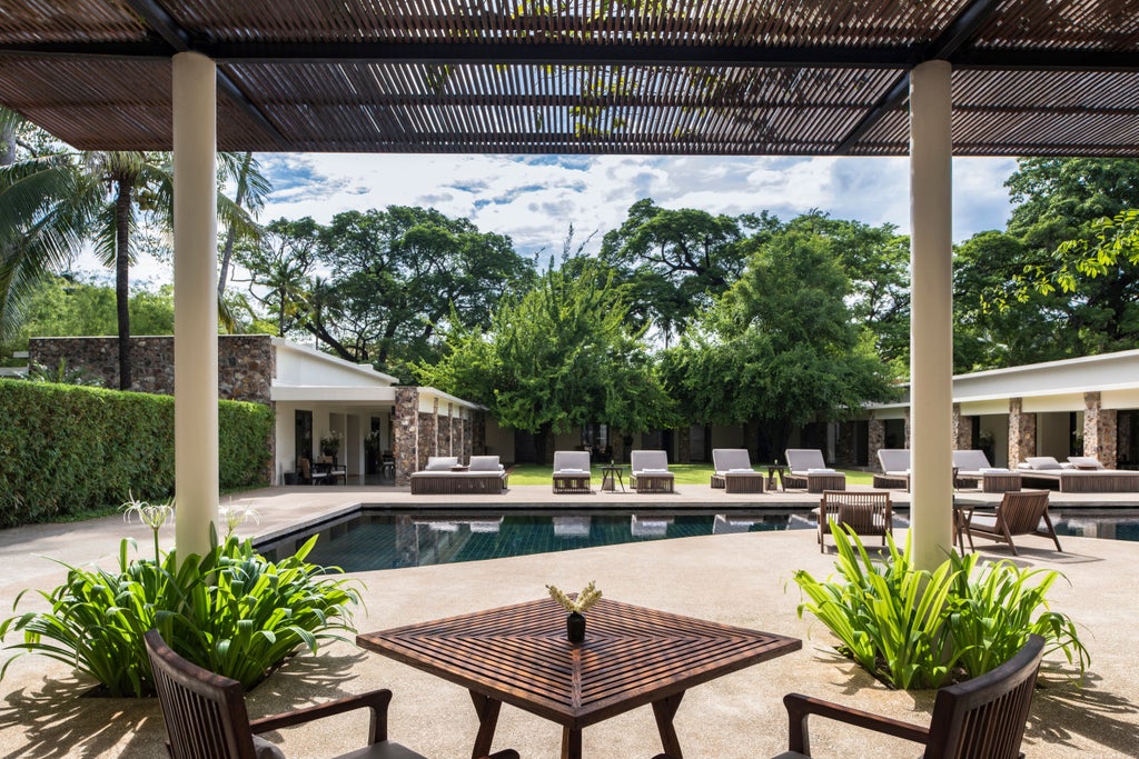 Ancient Khmer-inspired luxury resort with serene reflecting pool, stone pathways, manicured gardens and elegant teak pergolas in Siem Reap