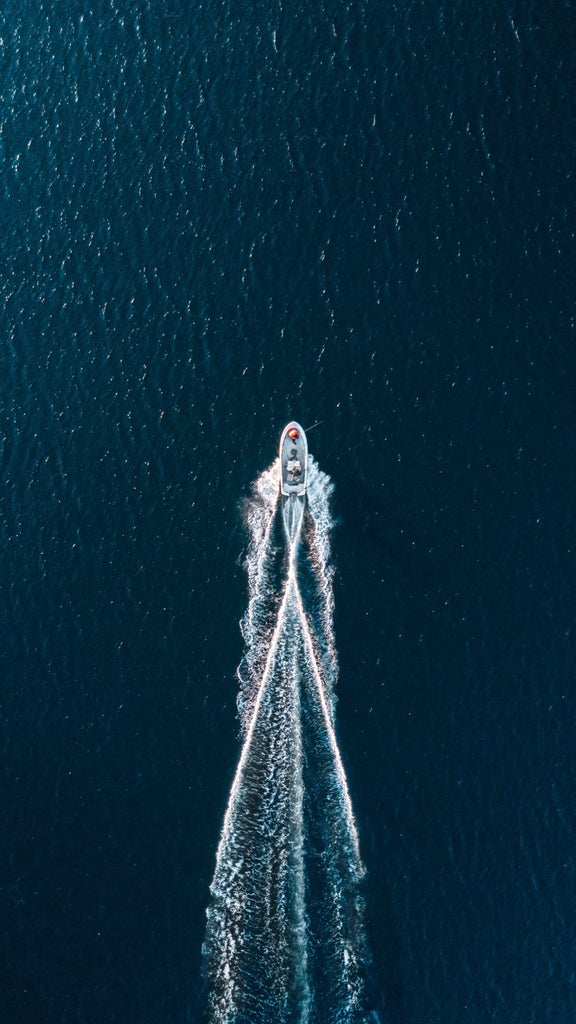 Speedboat gliding across crystal-clear Adriatic waters between Split and Hvar, with sun glinting off pristine white deck and azure waves