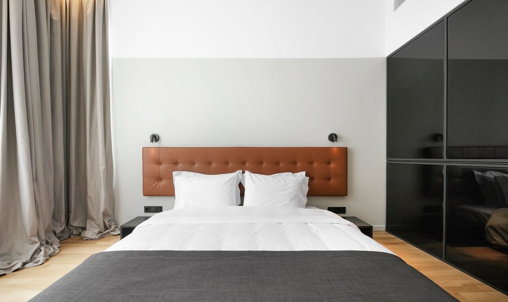 Minimalist hotel room with sleek design, soft neutral tones, modern furniture, and large window overlooking urban scenery in Thessaloniki, Greece