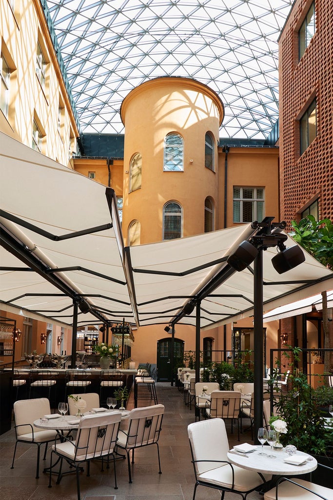 Elegant boutique hotel exterior with warm lighting, classic Swedish architecture, stone facade, and inviting entrance at dusk in Stockholm