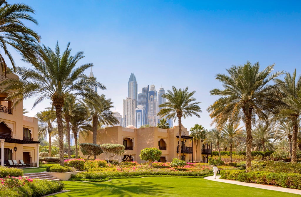 Opulent One&Only Royal Mirage resort with ornate Moroccan domes and archways reflecting in calm pools amid lush palm gardens at dusk