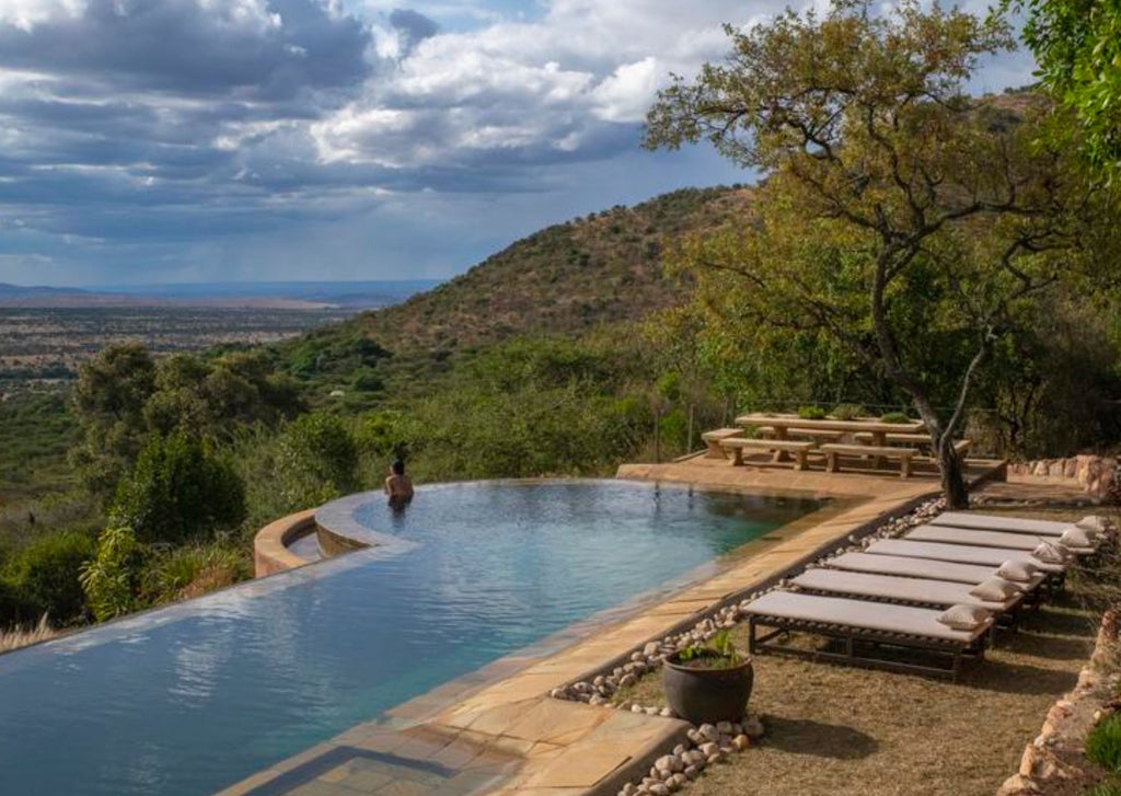 Elegant canvas safari tent with vintage colonial decor, draped bed, antique furniture and sweeping savanna views in Kenya