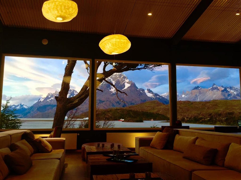 Upscale hotel overlooking Grey Lake in Torres del Paine National Park, featuring stone and wood facade with mountain backdrop at sunset