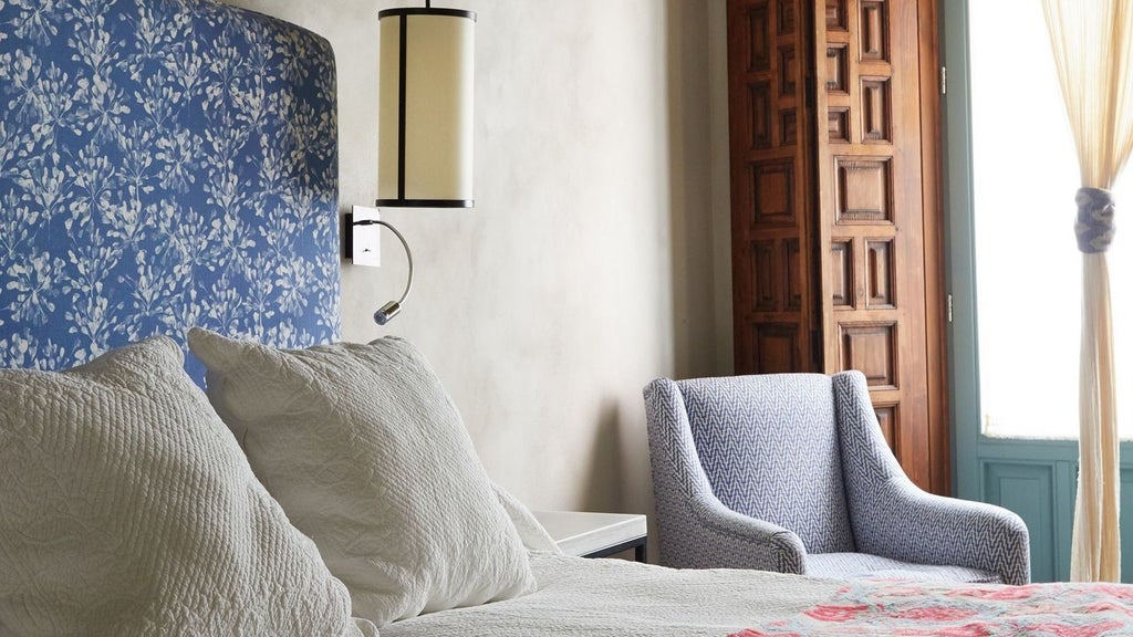 Elegant boutique hotel entrance in Seville with wrought iron gates, white-washed walls, and hanging lanterns framing a historic doorway