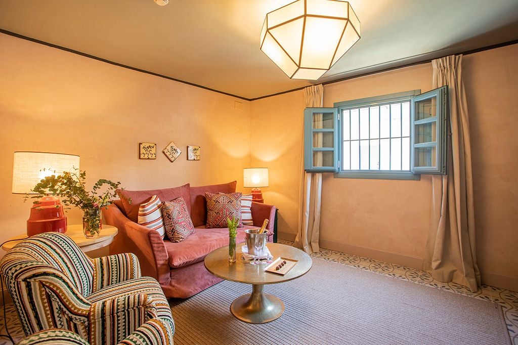 Elegant white-walled suite with traditional Spanish architectural details, ornate wooden furniture, and soft natural light in Seville hotel