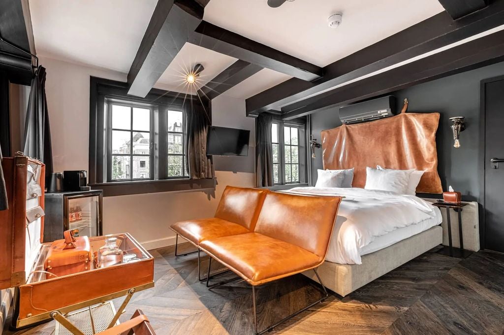 Historic Dutch boutique hotel with traditional brick facade, elegant white-framed windows, and charming canal-side location in Amsterdam