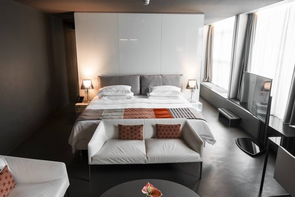 Elegant sky-level suite at Lido Palace with panoramic Italian coastline view, modern minimalist decor, king bed, floor-to-ceiling windows, and luxurious marble bathroom