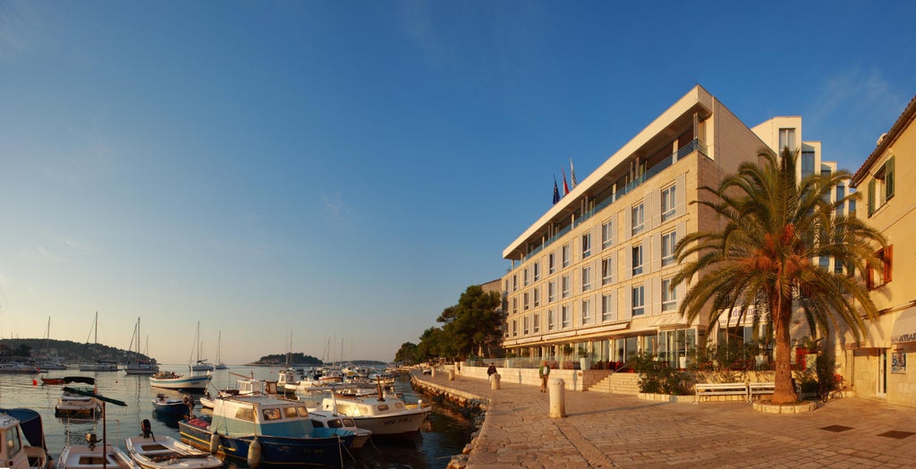 Elegant rooftop infinity pool of Adriana Hotel overlooking Hvar's marina and old town, with sunbeds and Mediterranean Sea views