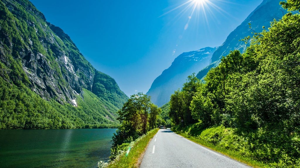 Scenic mountain bikes traversing lush green Norang Valley in Norway, with snow-capped peaks and a gourmet picnic spread against dramatic Nordic landscape