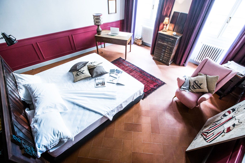 Elegant Florentine-style deluxe hotel room with rich wooden furnishings, ornate headboard, and classic Italian interior design elements