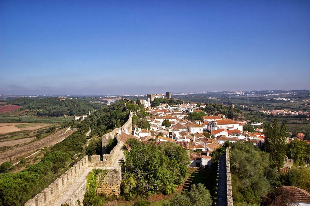 Medieval hilltop town of Obidos with white-washed buildings, terracotta roofs, and ancient stone walls overlooking Portuguese countryside