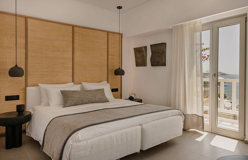 Luxury Deluxe Room at Hotel featuring private plunge pool overlooking azure Aegean Sea, minimalist white decor, and sweeping Mykonos coastline view