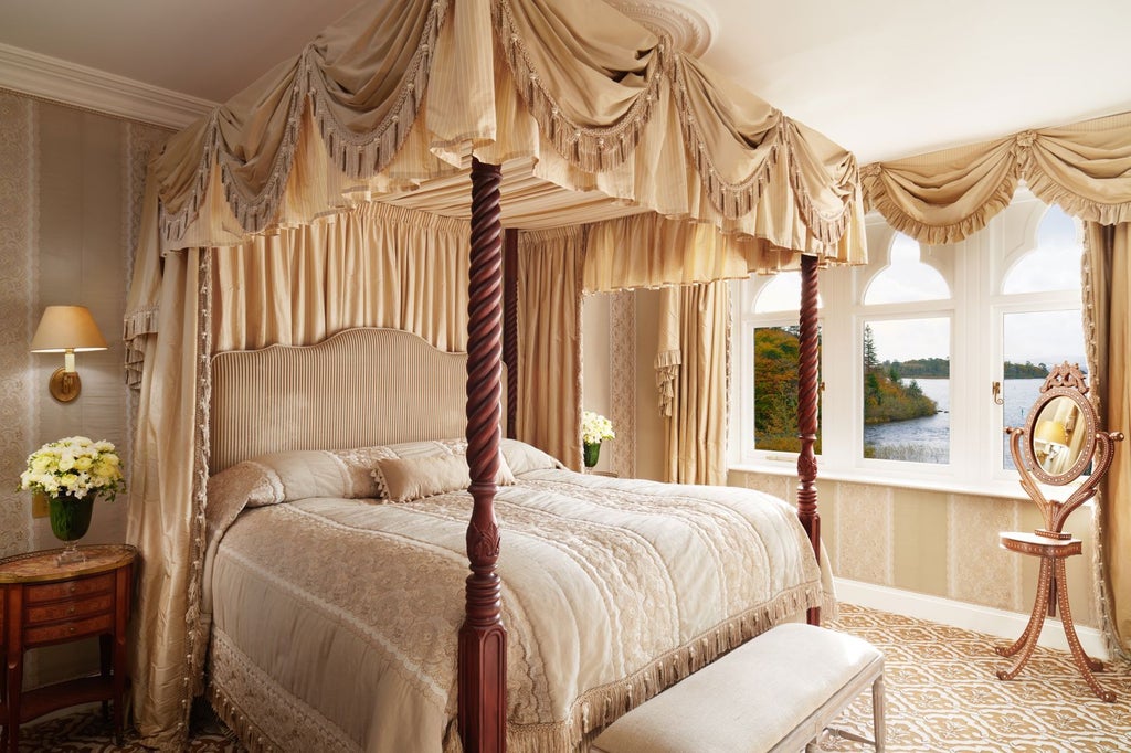 Elegant junior suite with antique furniture, four-poster bed, crystal chandelier, and floor-to-ceiling windows overlooking castle grounds