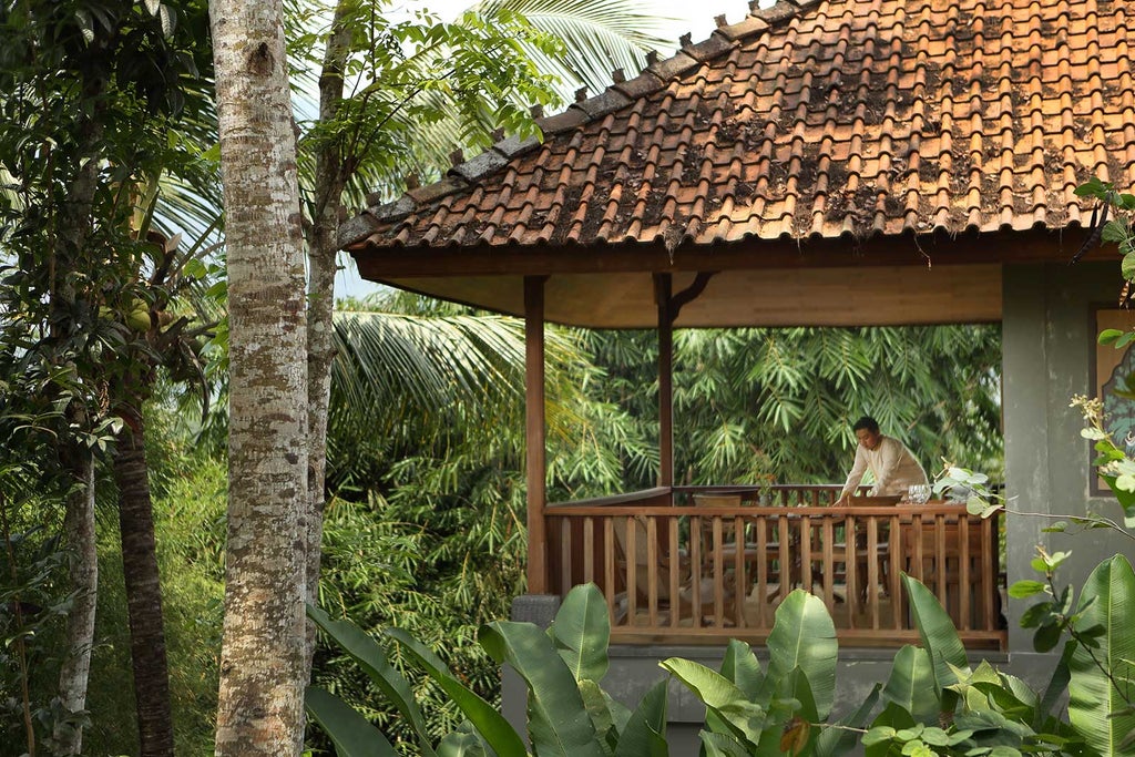 Luxury infinity pool overlooking lush jungle and distant mountains, with traditional Javanese-style pavilions and lounge chairs at sunset