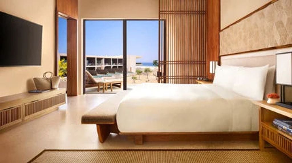 Sleek Japanese-inspired hotel suite with floor-to-ceiling windows, minimalist decor, and panoramic Pacific Ocean views from a private balcony