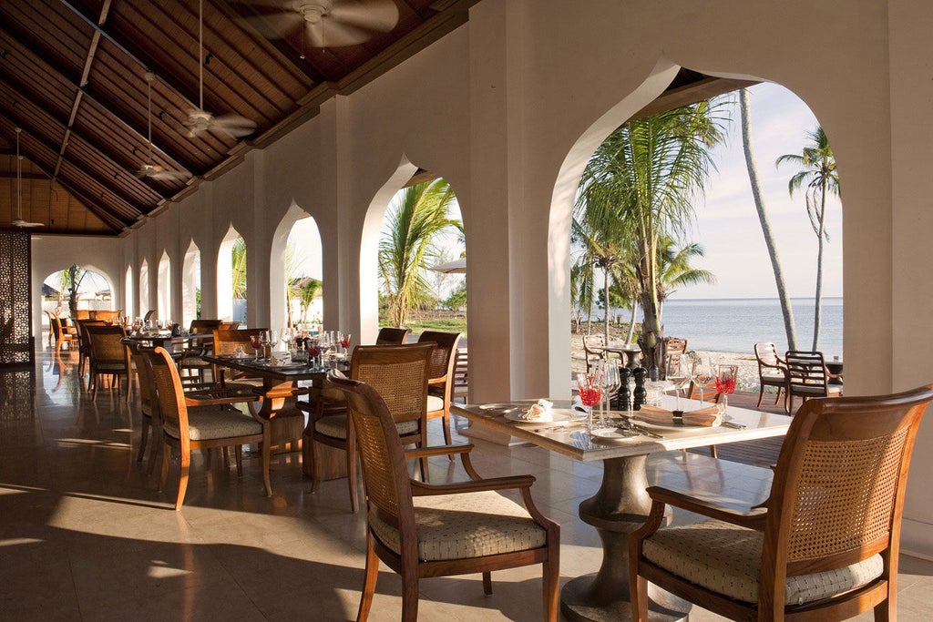 Luxurious beachfront villa at The Residence Zanzibar with private infinity pool, palm trees and pristine white sand beach at sunset