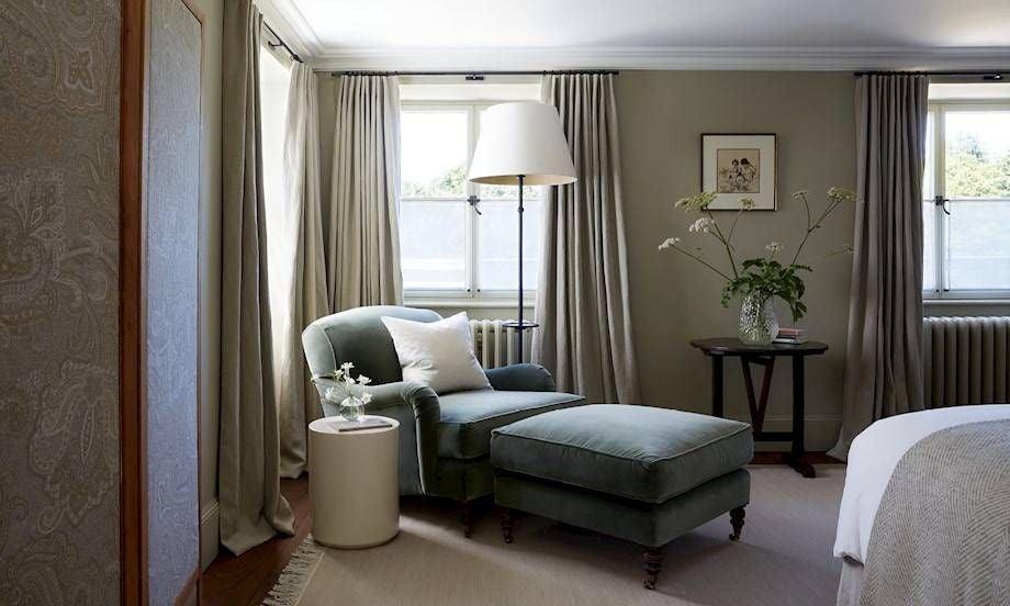 Elegant light-filled bedroom at luxury countryside estate, featuring soft neutral tones, minimalist design, and refined rustic wood furniture details