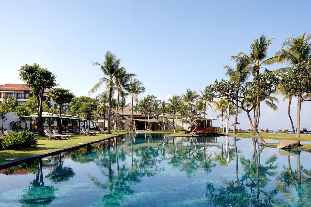 Luxurious infinity pool overlooking lush tropical jungle at The Samaya Bali resort, with sun loungers and traditional Balinese pavilions