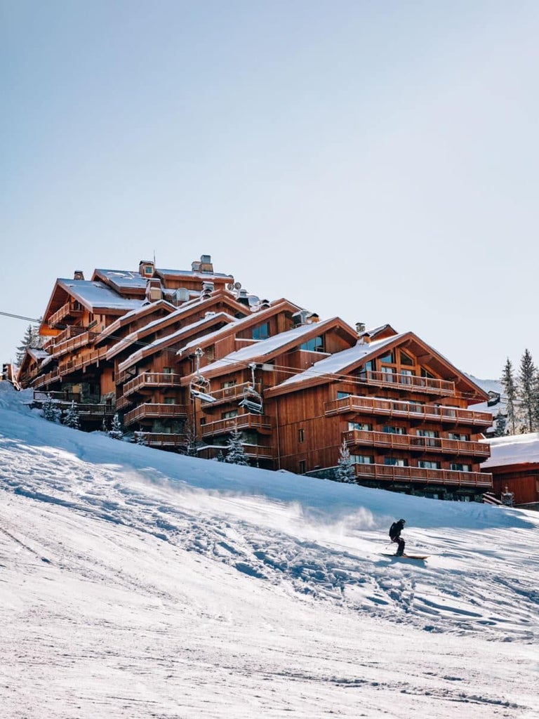 Luxurious alpine chalet-style hotel nestled in snowy Méribel mountains, featuring elegant wooden exterior and warm, inviting ski resort ambiance