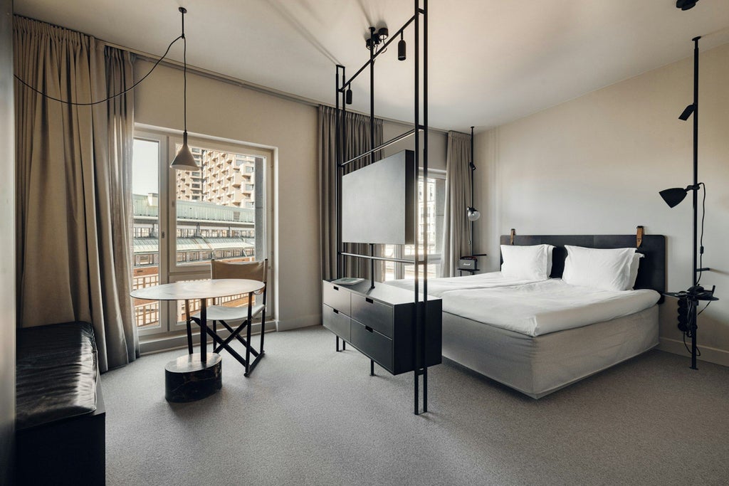 Modern Scandinavian design studio room with minimalist furniture, warm neutral tones, sleek wooden floors, and expansive city view through large windows at Blique hotel