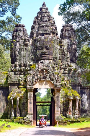 A tuk tuk passing through the gates of Angkor Thom
