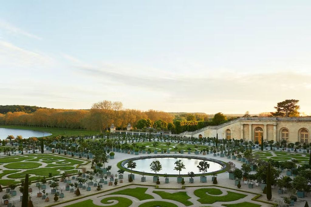 Opulent 18th-century French palace hotel with ornate golden details, classical architecture, and manicured gardens at sunset