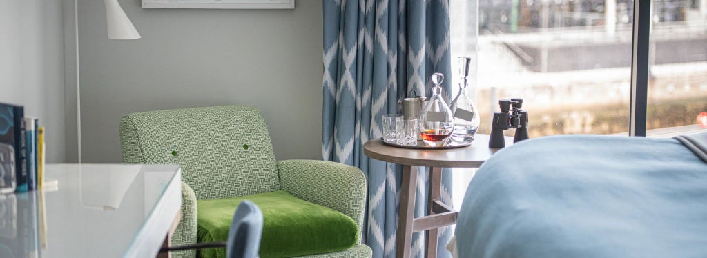 Modern deluxe hotel room with floor-to-ceiling windows overlooking Southampton Marina, featuring elegant contemporary furnishings and soft neutral color palette.