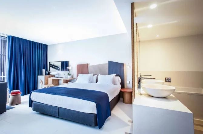 Modern loft-style hotel room with panoramic sea view, minimalist white decor, sleek furniture, and large windows overlooking Talamanca bay in Spain