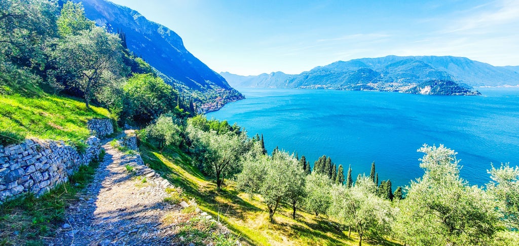 Panoramic view of Lake Como's emerald waters, surrounded by lush mountains and elegant waterfront villas under a golden sunset sky