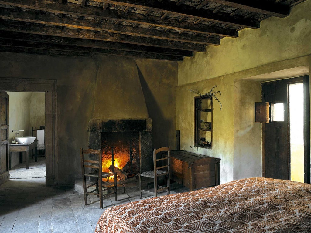 Rustic stone-walled bedroom with antique wooden bed, soft linens, and warm candlelight, showcasing traditional Italian mountain hospitality in Sextantio Albergo Diffuso