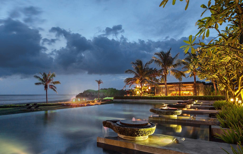 Luxurious beachfront villa with private infinity pool overlooking volcanic black sand beach and Indian Ocean at sunset in Bali