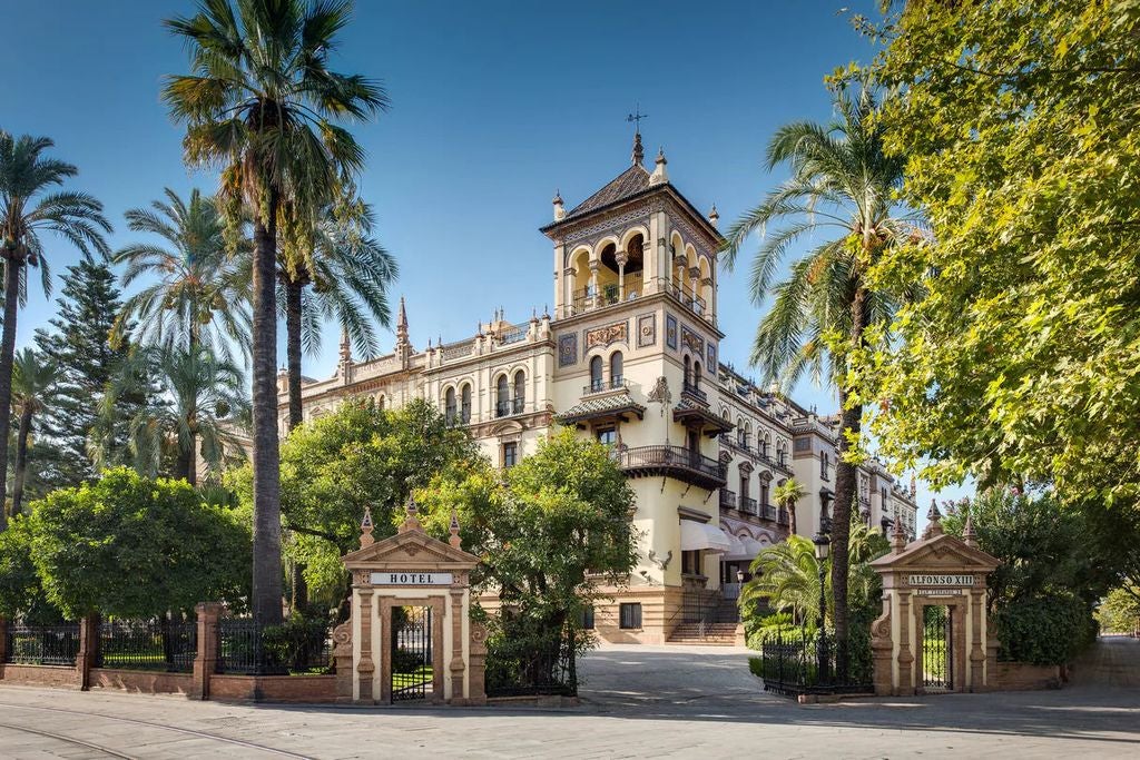 Grand historic Hotel Alfonso XIII exterior featuring ornate Moorish architecture, white facade, arched windows and manicured gardens in Seville