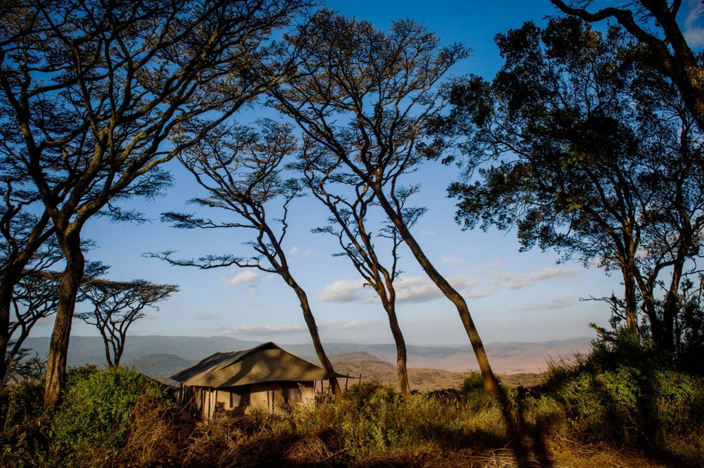 Luxurious safari tent perched on Ngorongoro Crater rim, with canvas walls, wooden deck and panoramic views of African savanna