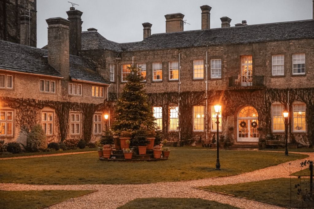 Elegant Cotswolds country estate with grand Georgian-style architecture, manicured gardens, and luxurious stone exterior surrounded by lush green landscape