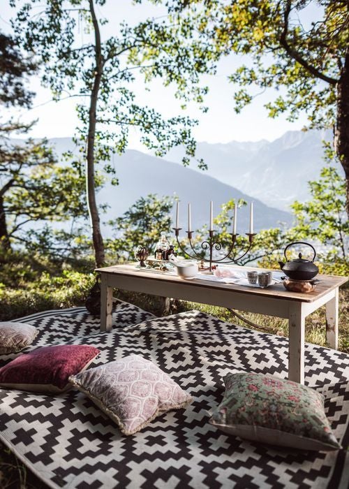 Elegant hilltop castle hotel with stone facade and balconies overlooks lush Italian mountainside, surrounded by manicured gardens and cypress trees