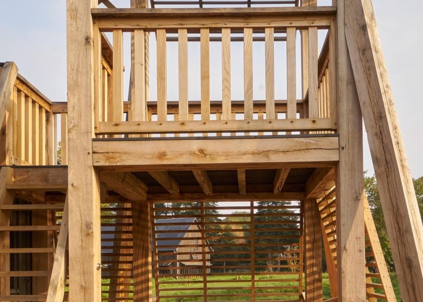 Elegant treehouse-style room at Les Sources de Cheverny, featuring rustic wooden furnishings, plush bedding, and large windows overlooking lush French countryside