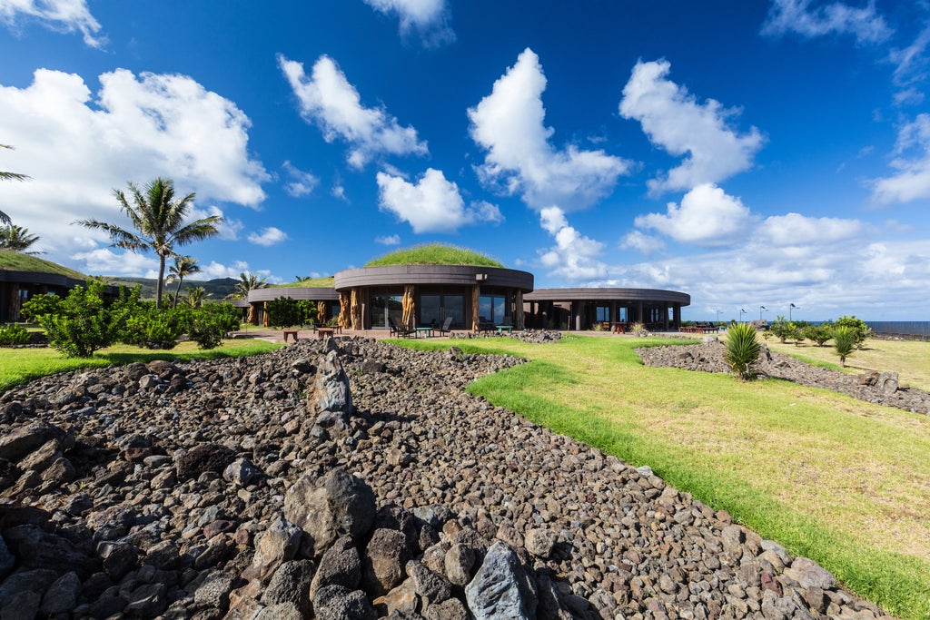 Modern luxury resort with curved stone walls and floor-to-ceiling windows overlooking the Pacific Ocean coastline of Easter Island