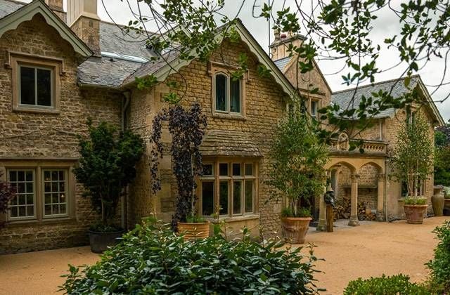 Luxurious stone facade of Homewood Hotel & Spa, nestled in scenic UK countryside, featuring elegant architecture and pristine landscaped gardens at dusk