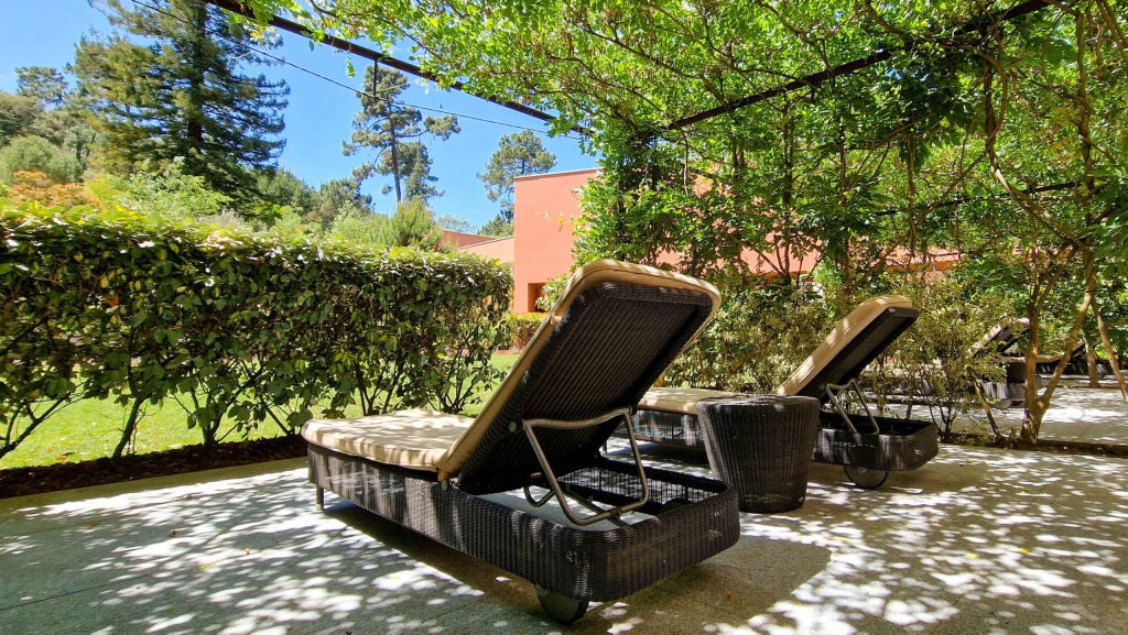 Luxurious garden-view deluxe room at Vidago Palace Hotel, showcasing elegant decor, plush bed, and verdant Portuguese landscape through expansive windows