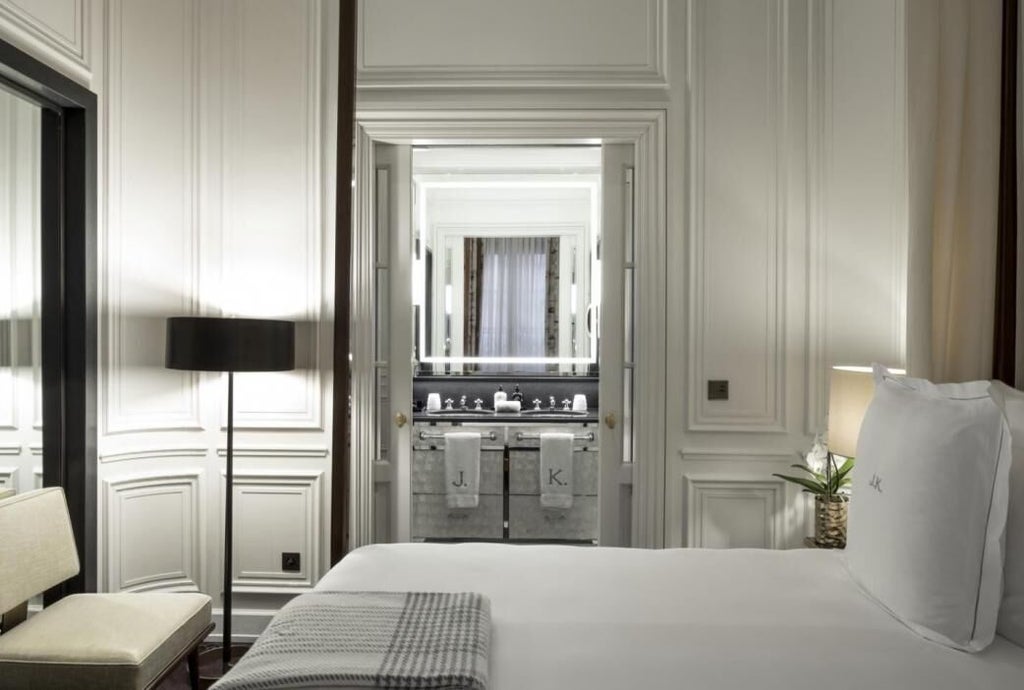 Luxurious Parisian hotel suite with elegant white furnishings, plush king bed, marble bathroom, and chic French-inspired design by renowned hospitality brand