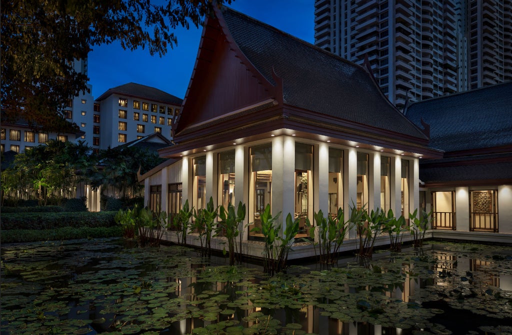 Elegant Thai-style luxury hotel with reflecting pool, surrounded by tropical gardens and featuring ornate golden architectural details