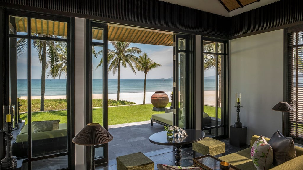 Vietnamese beachfront villa with private infinity pool at Four Seasons Nam Hai, surrounded by palm trees and tropical gardens at sunset