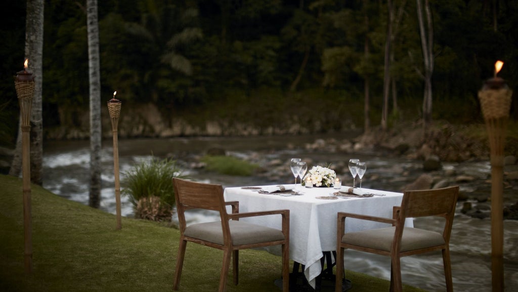 Luxurious infinity pool overlooking lush tropical jungle with traditional Balinese architecture and private villa terraces at sunset